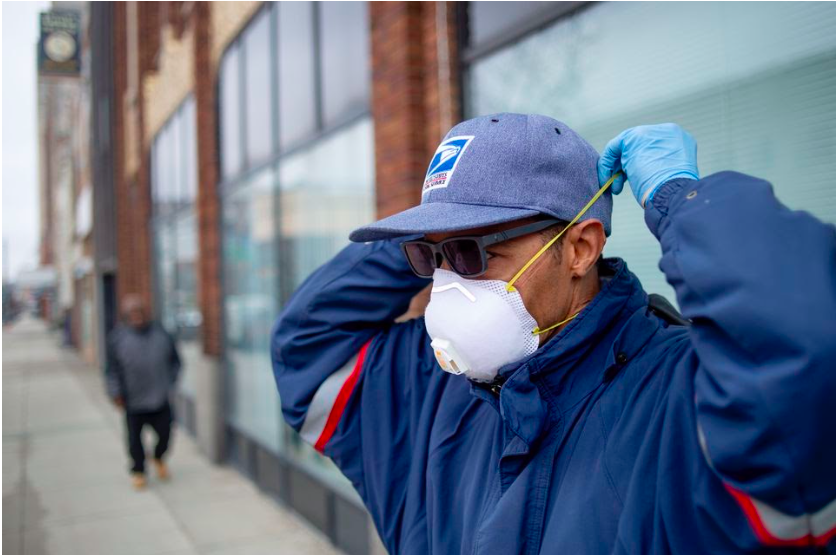 Flint postal worker Mark Fransioli delivers mail wearing gloves and a mask on Monday, March 23, 2020 in Flint. All Michigan residents and most businesses are required to stay in their homes under an executive order issued by Gov. Gretchen Whitmer to slow the spread of the coronavirus COVID-19.