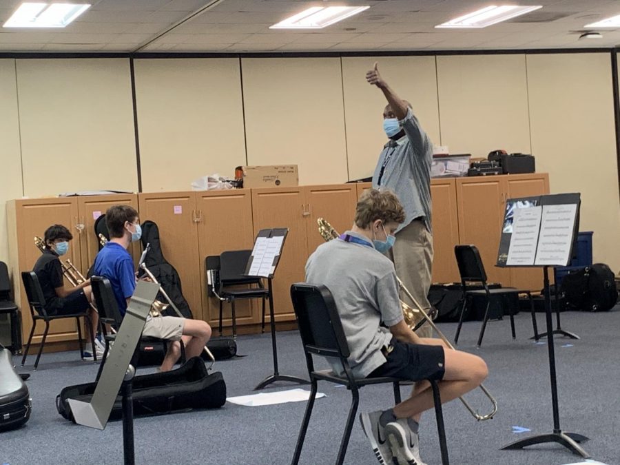 Music Director Rufus Jones conducts hybrid band rehearsal. The Music Department is one of the most impacted groups at school, as it is difficult to keep audio in sync and practice instruments when some students are online and some are in person.