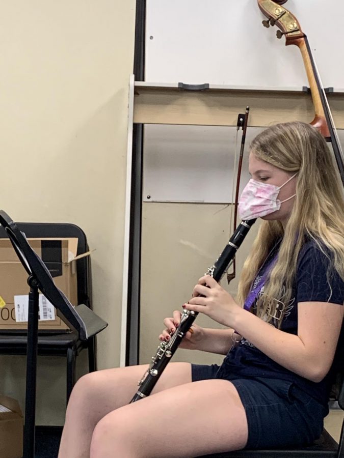 A music student plays her instruments during class. Students with instruments like the clarinet must wear masks while playing.