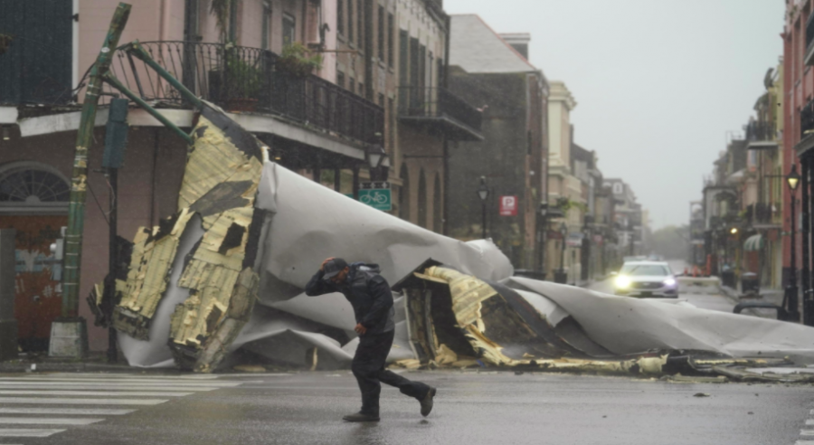 A man passes by a section of roof that was blown off of a building in the French Quarter by Hurricane Ida winds, Sunday, Aug. 29, 2021, in New Orleans.