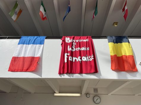 A student-made flag hangs alongside a French and Belgian flag in the Atrium.