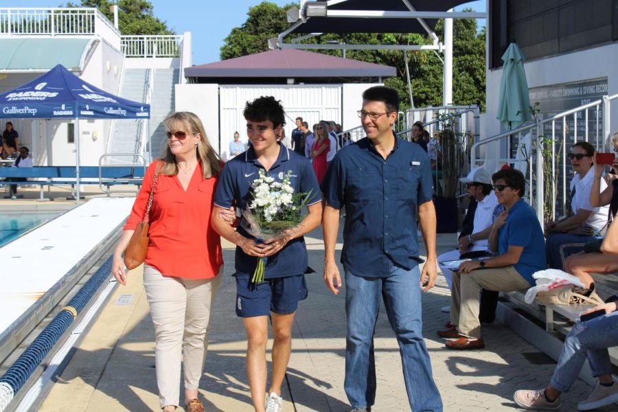 Senior Evan Abril walks with his parents during the boys water polo Senior Day ceremony.