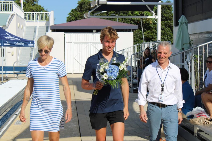 Senior Lukas Schoenwald walks with his parents during the boys water polo Senior Day ceremony.