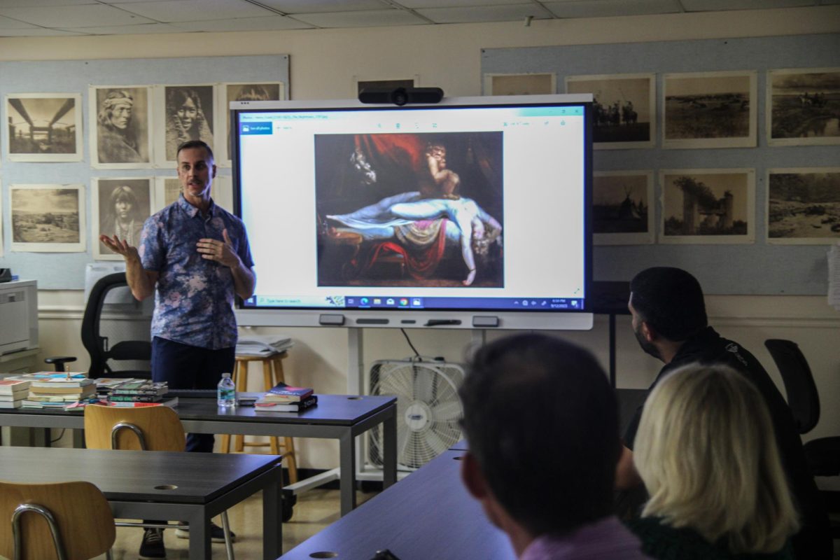English teacher Neil De La Flor analyzes artwork as a part of his Back to School night activities.
