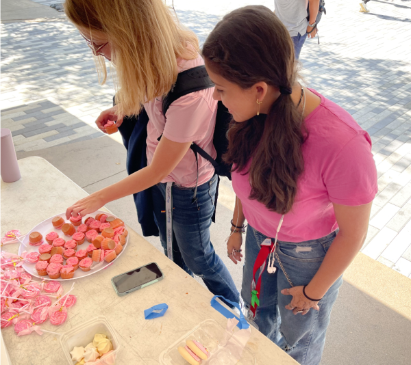 Junior Claire Roades and senior Constanza Prato purchase baked goods. The stands were open during A lunch and B lunch outside of the cafeteria. This made it very accessible for students to see the event and participate at their leisure.
