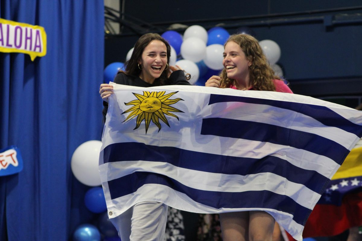 Two students carry the Uruguayan flag. Each year, the assembly begins with a flag parade consisting of every country represented through the student body. Students often cheer loudest for the countries they are from.