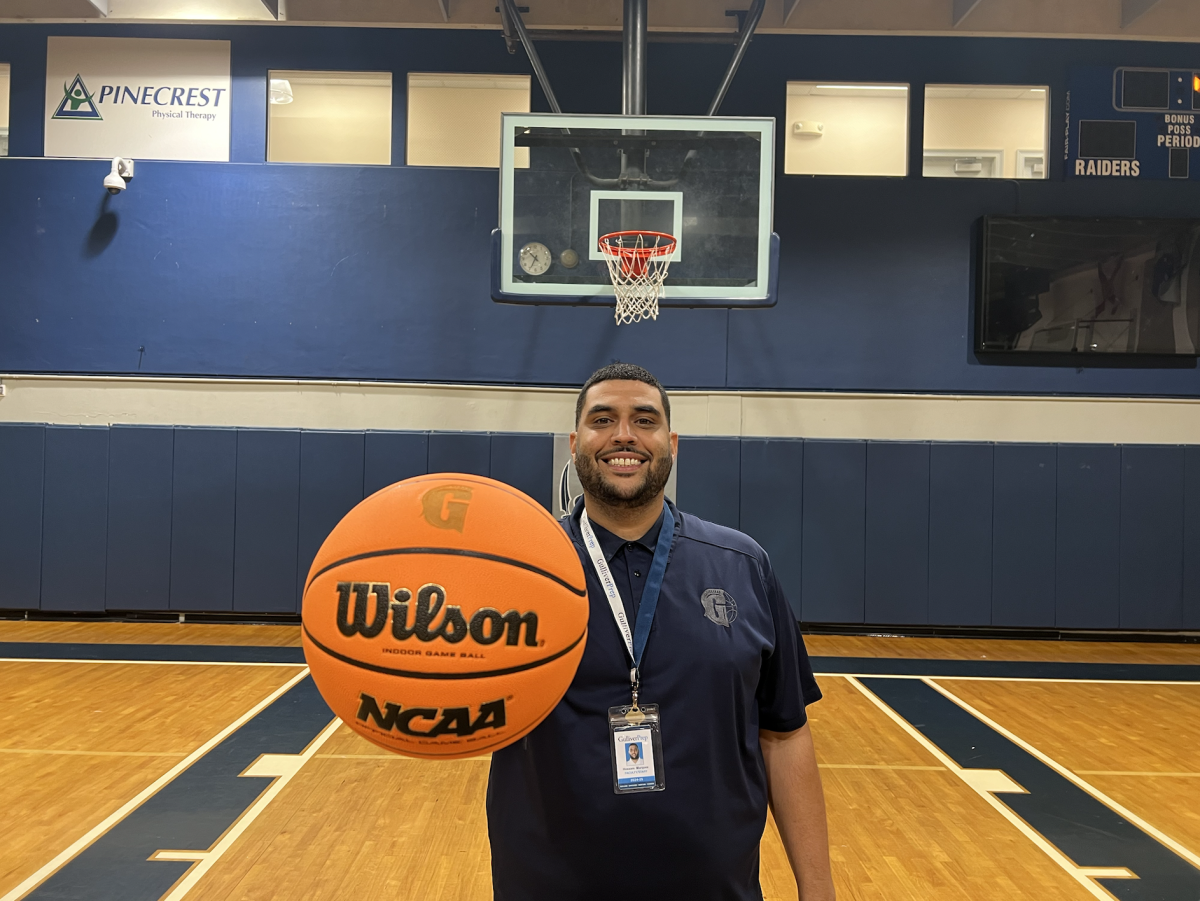 Coach Marquez posses with the basketball in the Blue Dungeon. Marquez prepares for the new season as the Varsity team will face different opponents, switching their district.