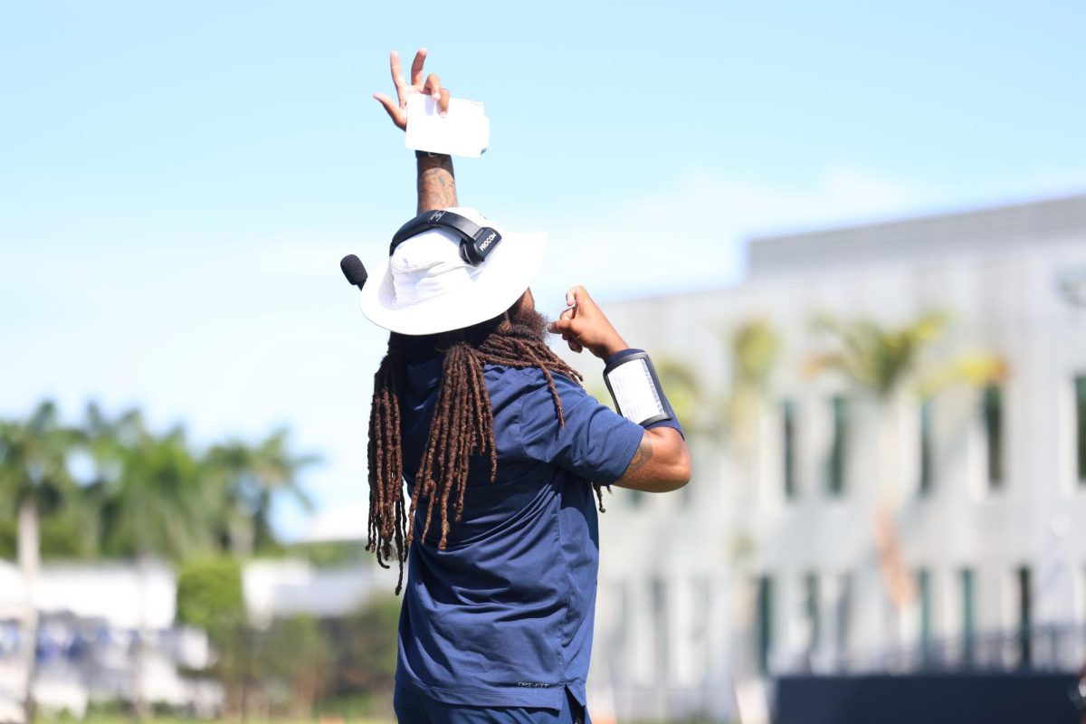 Offensive coordinator Tony Gaiter IV signals the play call to sophomore quarterback Jonathan Walker. Gaiter has brought a fast paced spread option scheme to the team relying on his wide receivers to make plays.