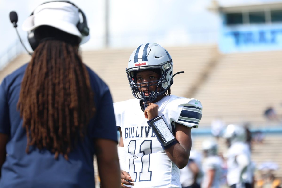 Sophomore Jonathan Walker talks to offensive coordinator Tony Gaiter IV for the playcall. Walker has shown a wide range of skills showing he can be a pocket passer while be able to scramble for positive yards.  