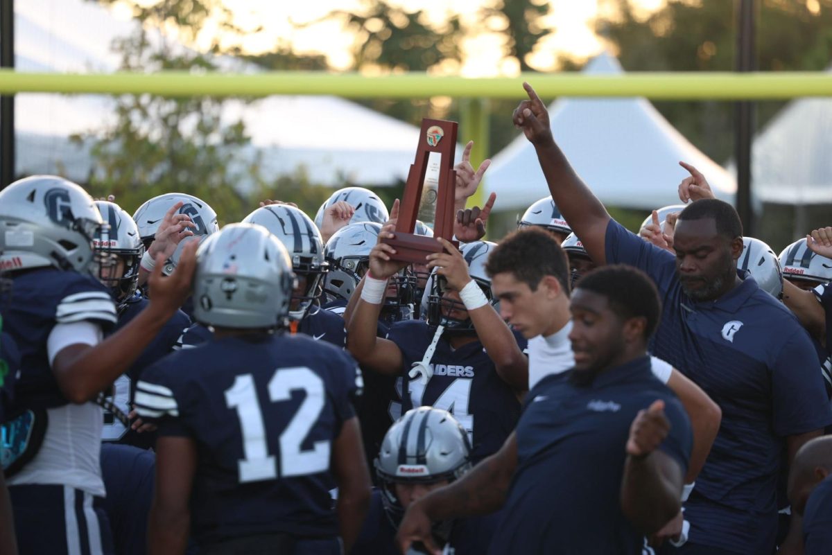 Players and coaches celebrate after the huge homecoming victory, joyfully holding the district championship trophy. Even though it wasn’t a district game, they embraced the moment and enjoyed their time together. The smiles on their faces showed how hard they worked to achieve this win.