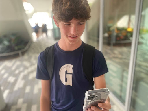 Freshman William Allen smiles as he looks at his iPhone 16. Allen has recently purchased the iPhone and has noticed significant differences in the camera qualities. 