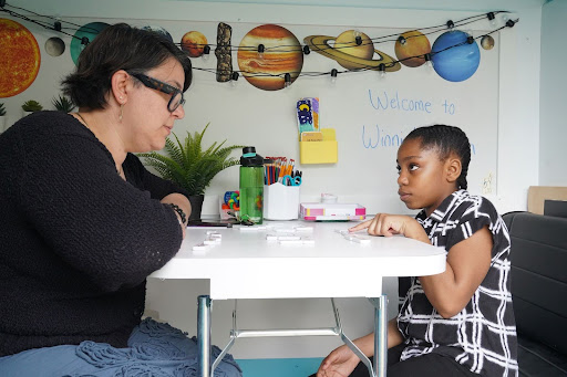 Education support coordinator Loren Kurpiewski plays a word-based domino game with 9-year-old Jayden during a weekly visit with Winnie's Wagon mobile tutoring van in Pittsburgh's Northview Heights neighborhood on April 30, 2024. The van serves as a mobile classroom providing tutoring space for children of families experiencing homelessness, a program organized through the Homeless Children’s Education Fund. (Sebastian Foltz/Pittsburgh Post-Gazette/TNS)