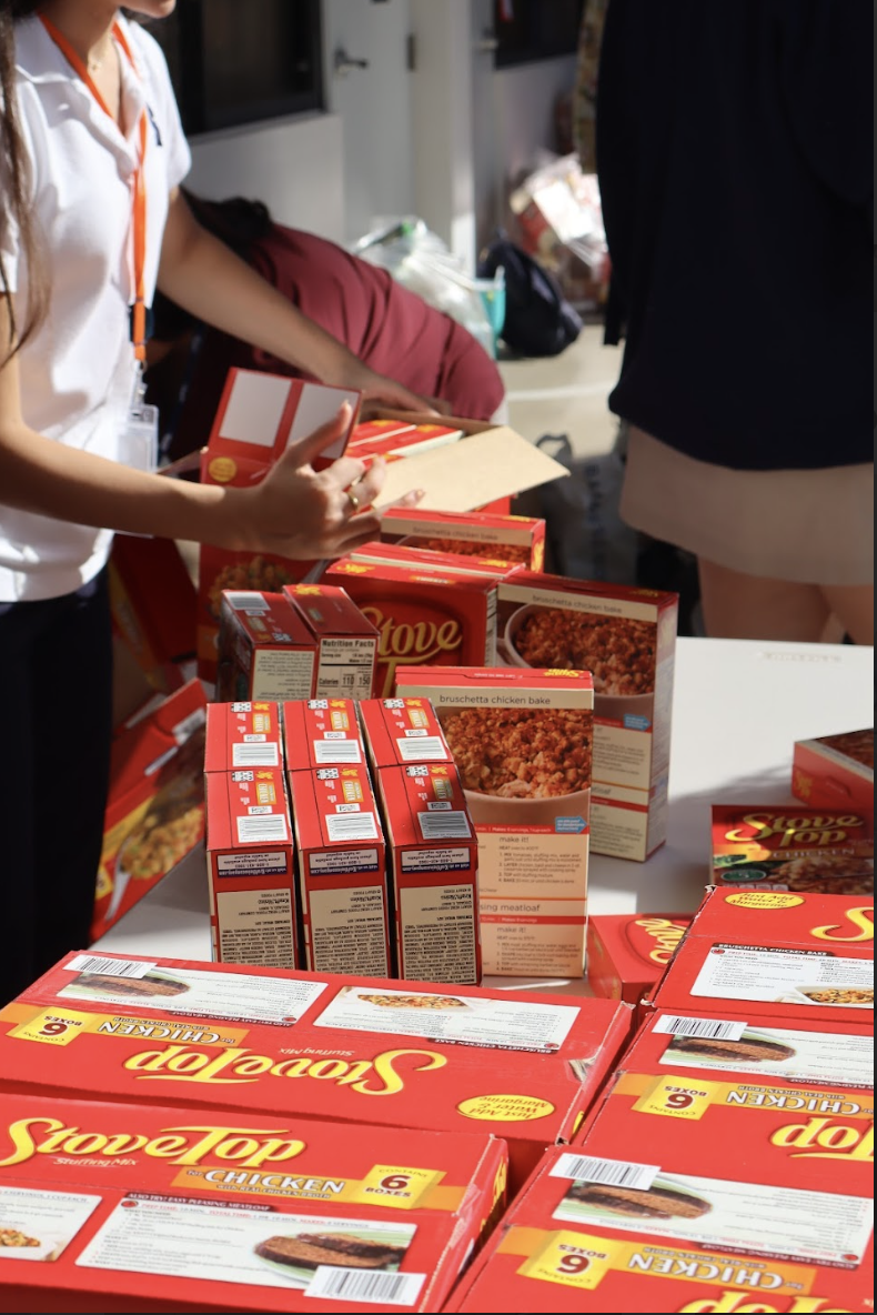 Student volunteers collect stuffing boxes and other Thanksgiving staples before placing them into the meal boxes. This effort is part of Dish Out Kindness’s mission to ensure Miami families have access to full meals during the holiday season.