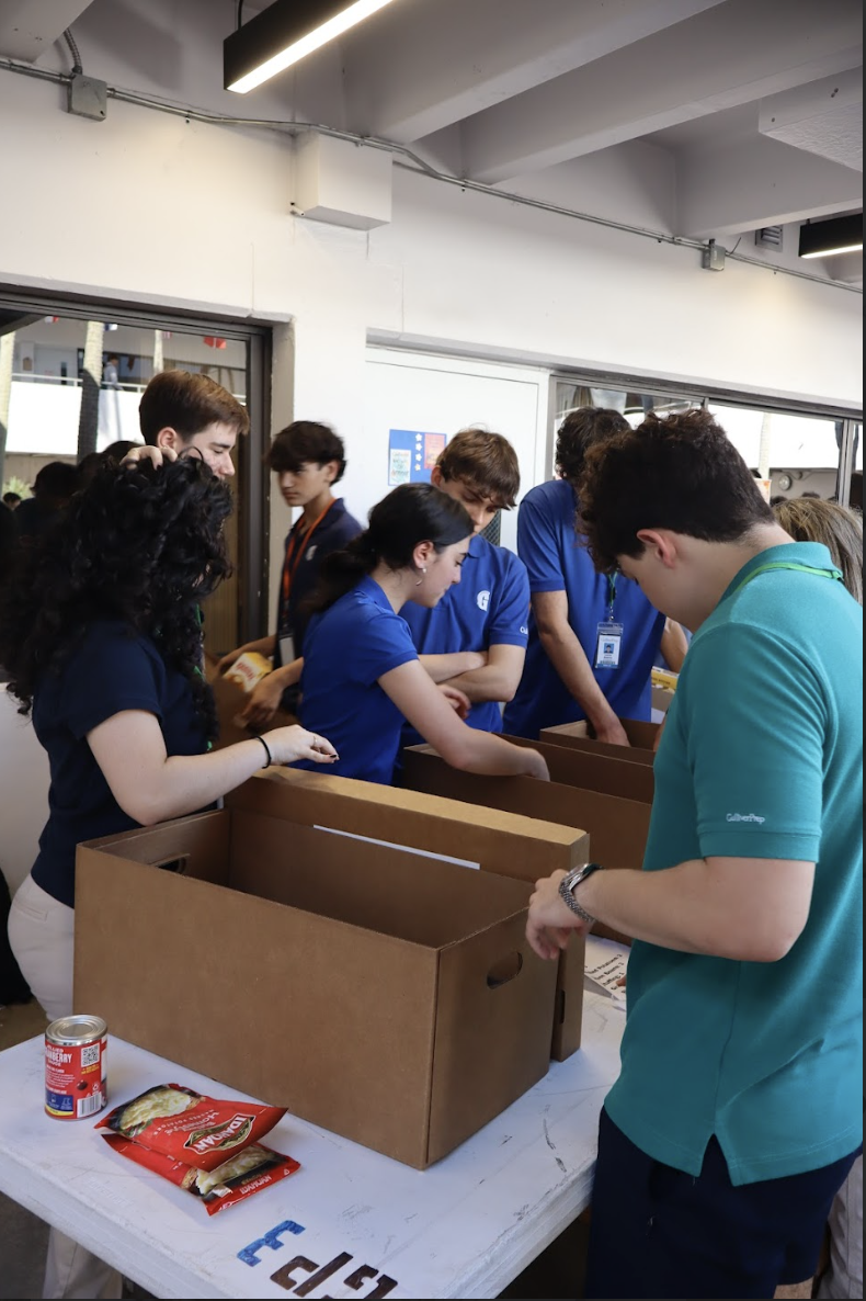 Volunteers and Dish Out Kindness board members work together in the atrium, organizing ingredients and filling boxes with essential Thanksgiving items. Club leaders guided each station to keep the packing process efficient and ensure all 400 meals contained the necessary items.