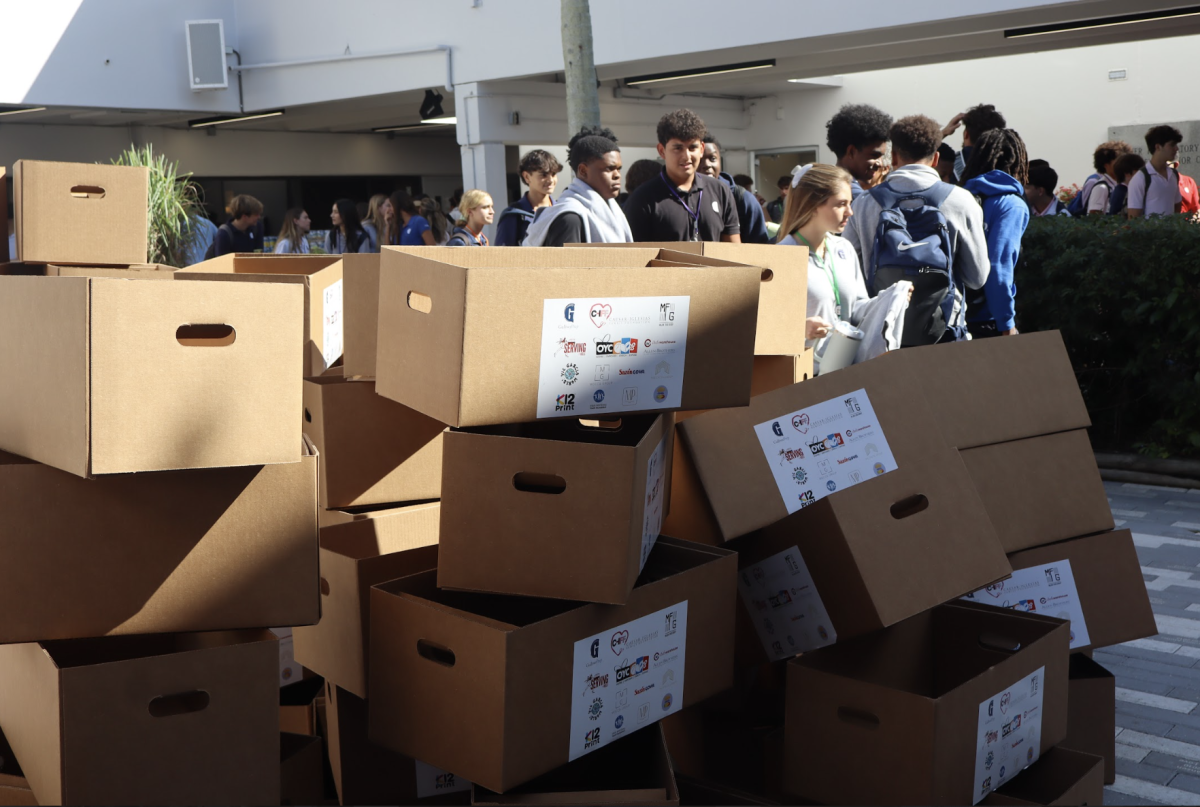 Dozens of empty cardboard boxes wait to be filled as students move through packing stations during the Dish Out Kindness Thanksgiving Drive. The boxes will later be loaded with ingredients donated for 400 complete Thanksgiving meals to support families in Overtown.