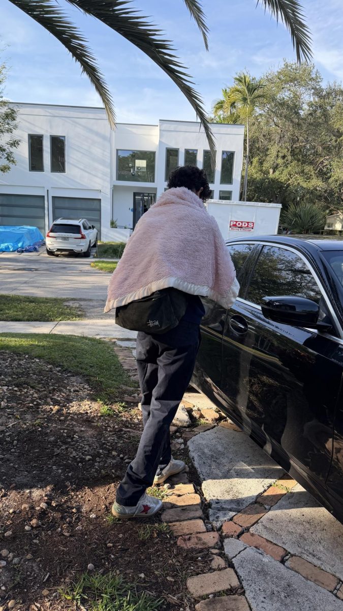 Sophomore Zee Tobins wears a blanket over his shoulders while leaving the house this cold morning. Temperatures dropped into the 40s earlier this week following a brief cold front. The school’s dress code remained in effect despite cooler conditions.