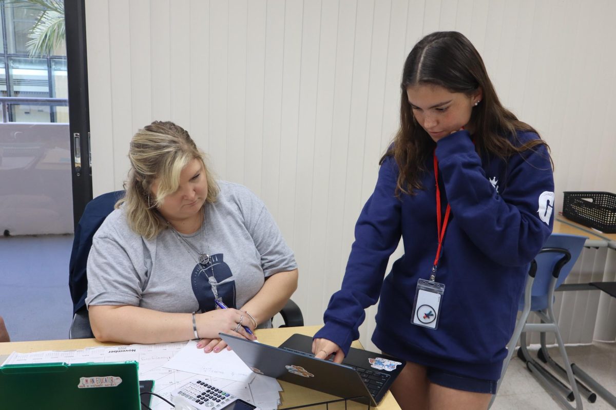Senior Sydney Brown approaches Mrs. Taylor, asking for clarification on an assignment. Taylor explains the problem and points out what to focus on. Their teamwork helps the student understand more clearly.