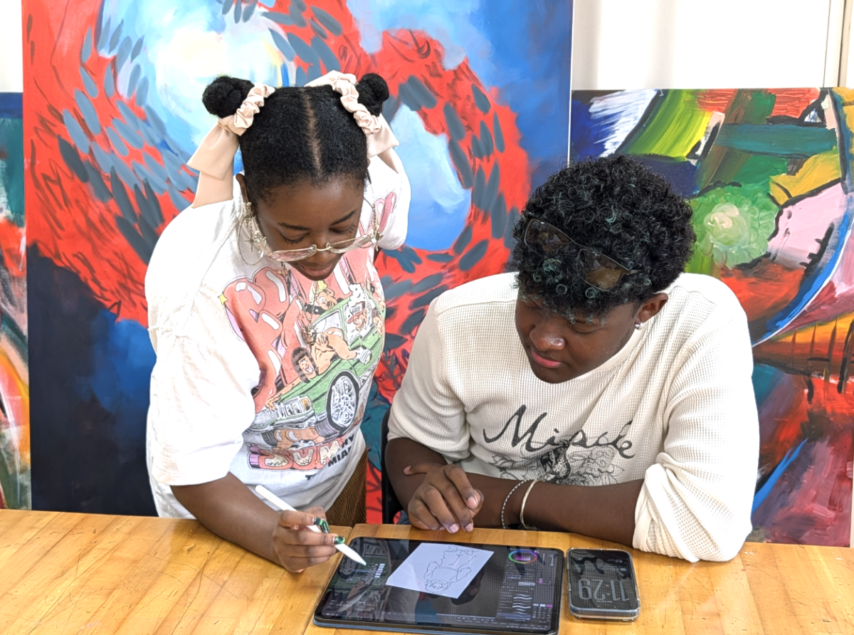 Burrote helping junior Wolf Augustin by showing him hands-on how to use the Procreate system settings. Augustin, an NAHS officer, helped plan the event for the honor society and participated in the workshop. 