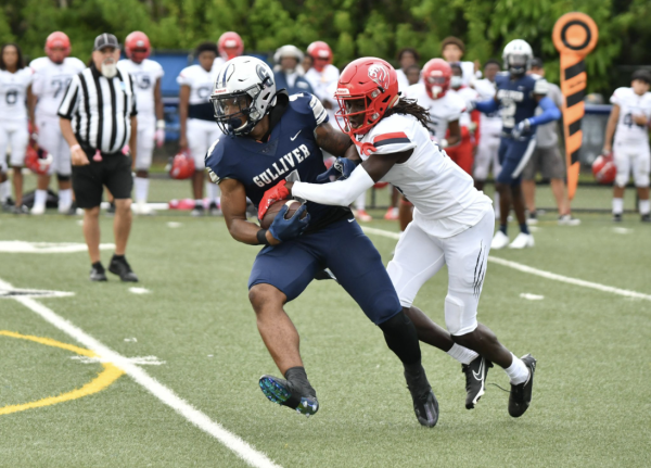 As the opponent throws himself on top of senior Decarlo Donaldson, he keeps pursuing forward. His strength and determination helped him stay focused. “I put my mind and my strength to keep running,” Donaldson said. Photo by Foxmar.